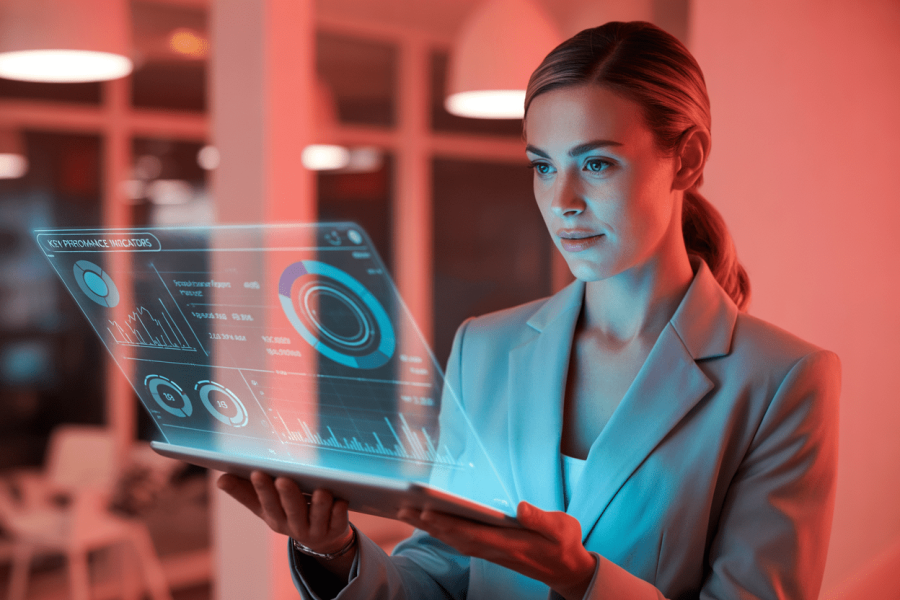 A professional woman in a light blue blazer holds a laptop displaying vibrant data visualizations and key performance indicators.